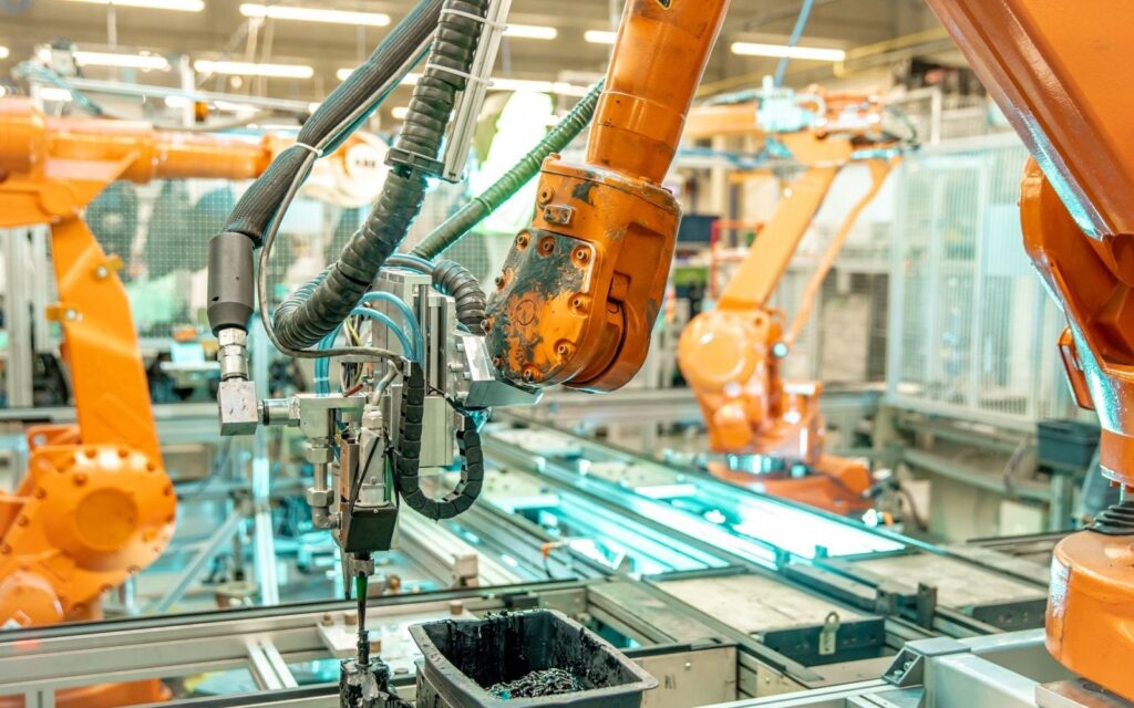 Detail průmyslového robotického ramene nanášejícího materiál na zpracovatelské lince.